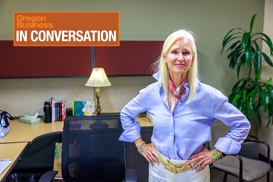Vernier Science Education CEO Jill Hedrick, wearing a blue button-down shirt and a scarf, stands in front of a desk.